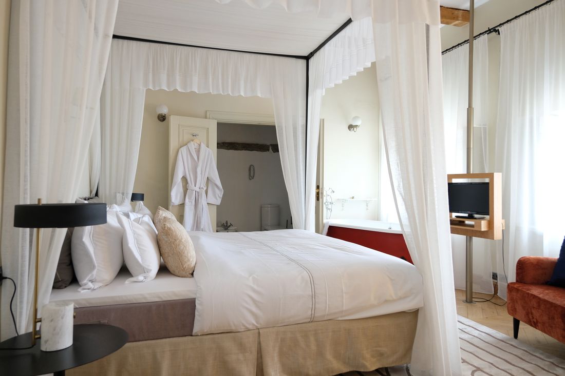 A canopy bed beside a freestanding tub
